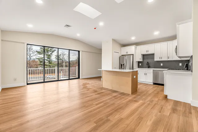 a large kitchen with stainless steel appliances granite countertop a large counter top a stove and a wooden floors