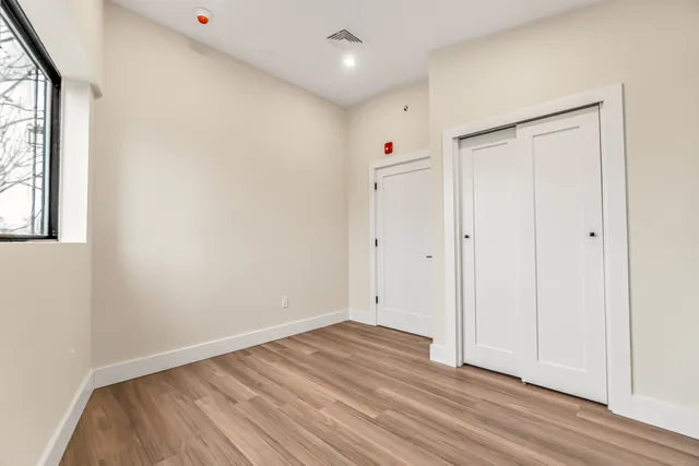 an empty room with wooden floor and windows