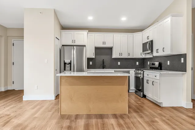 a kitchen with stainless steel appliances granite countertop a stove top oven a sink and white cabinets