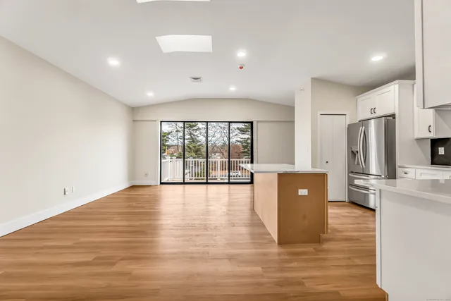a view of kitchen with stainless steel appliances a refrigerator and wooden floor