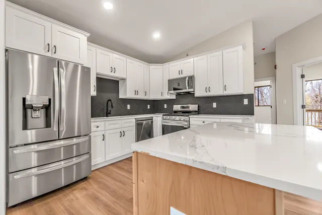 a kitchen with kitchen island a white cabinets and stainless steel appliances