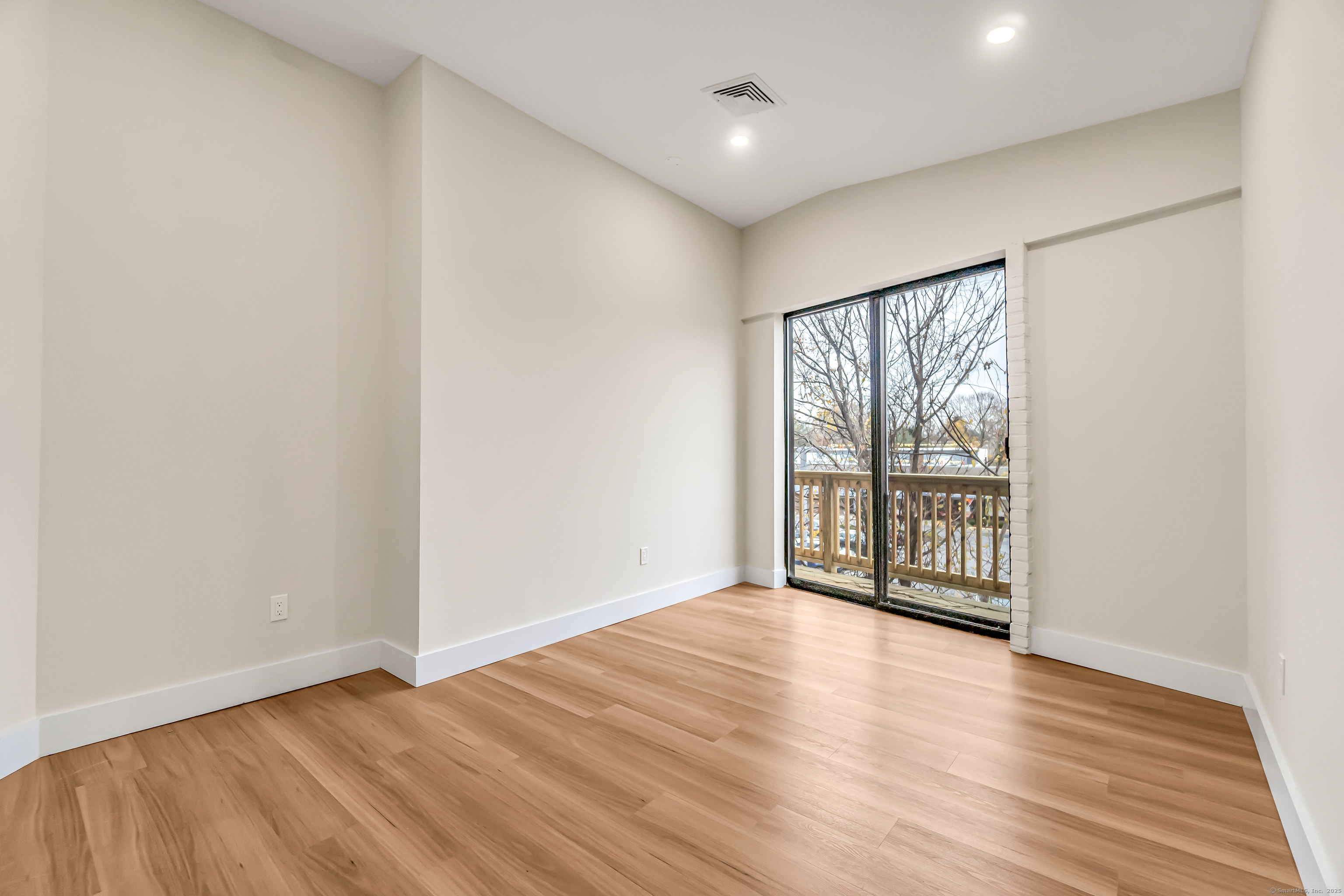 937 Post Road, Unit 3A Fairfield, CT 06824 - Photo 10 of 24 a view of an empty room with wooden floor and a window
