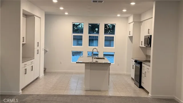 a kitchen with stainless steel appliances kitchen island granite countertop a refrigerator and a sink