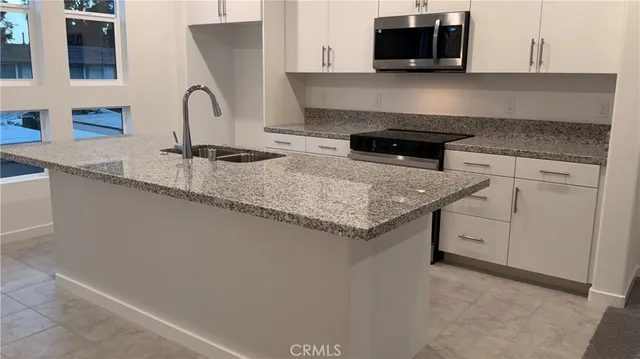 a kitchen with granite countertop white cabinets and a stove