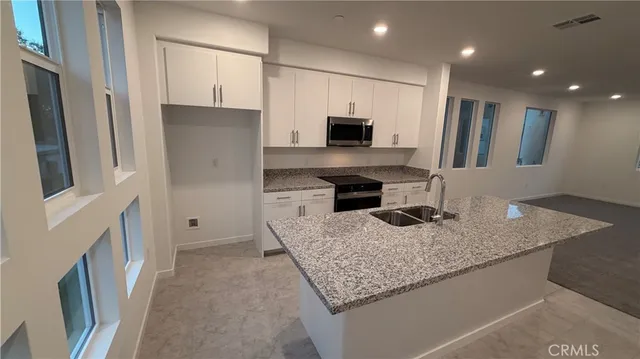 a kitchen with stainless steel appliances granite countertop a sink refrigerator and microwave