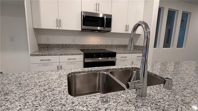 a kitchen with granite countertop a stove a microwave a sink and a counter top space