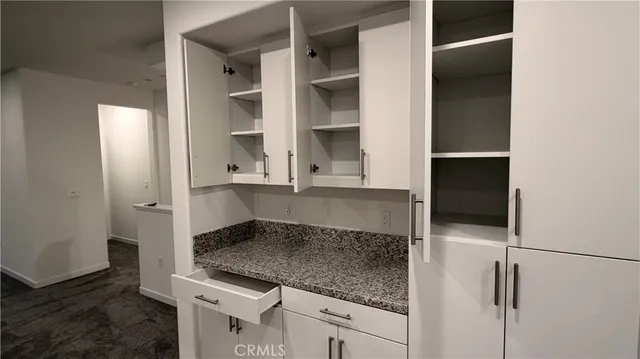 a kitchen with a granite countertop sink and white cabinets