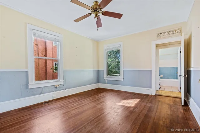 an empty room with wooden floor fan and windows