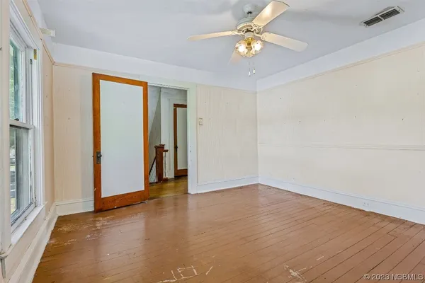 a view of an empty room with wooden floor and a window
