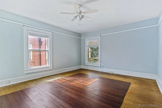 a view of an empty room with window and wooden floor