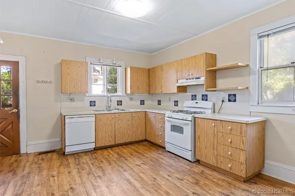 a kitchen with a sink cabinets wooden floor and stainless steel appliances