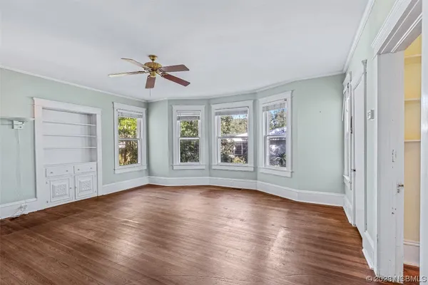 a view of empty room with wooden floor and fan