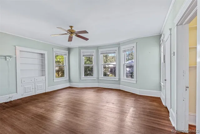 a view of empty room with wooden floor and fan