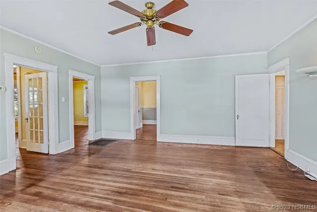 an empty room with wooden floor chandelier fan and windows