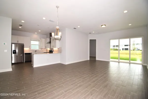 a view of an empty room and kitchen with a floor to ceiling window