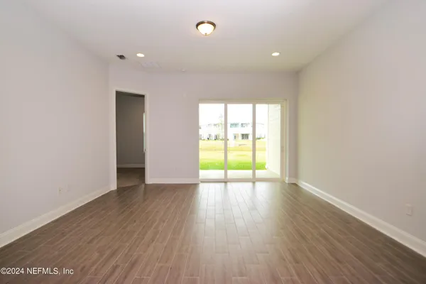 an empty room with wooden floor and natural light