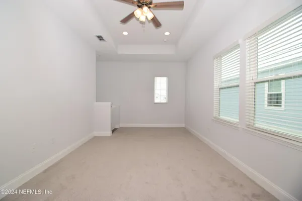 an empty room with windows and fan