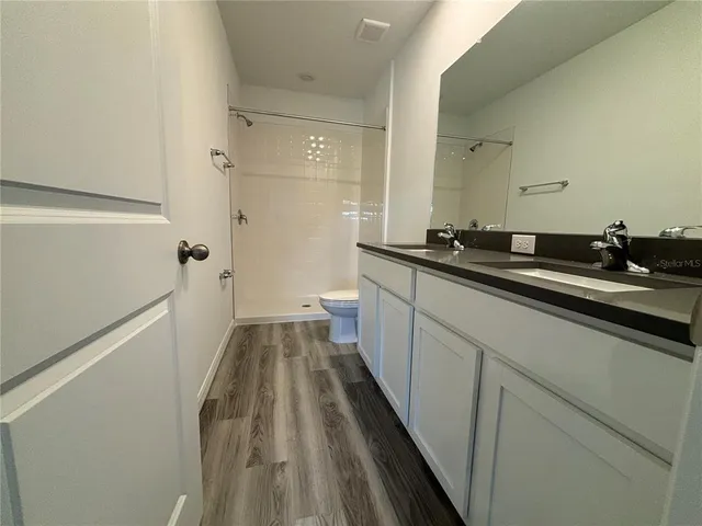 a bathroom with a toilet a sink and wooden floor