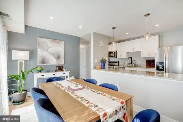 a kitchen with kitchen island a stove a refrigerator a sink a dining table and chairs with wooden floor