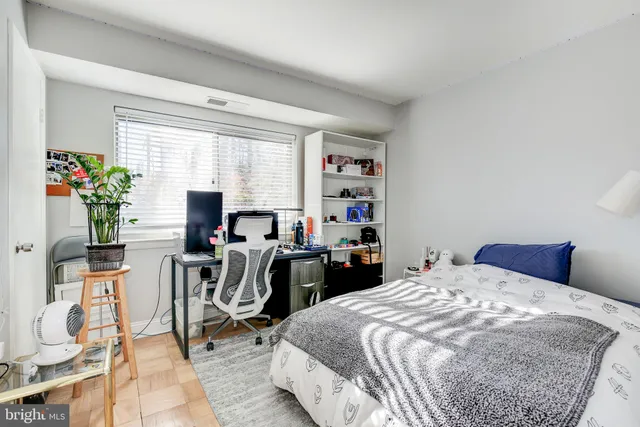 a bedroom with a bed a computer on the desk and chair