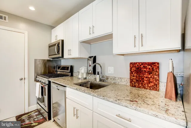 a kitchen with stainless steel appliances granite countertop a sink stove and cabinets