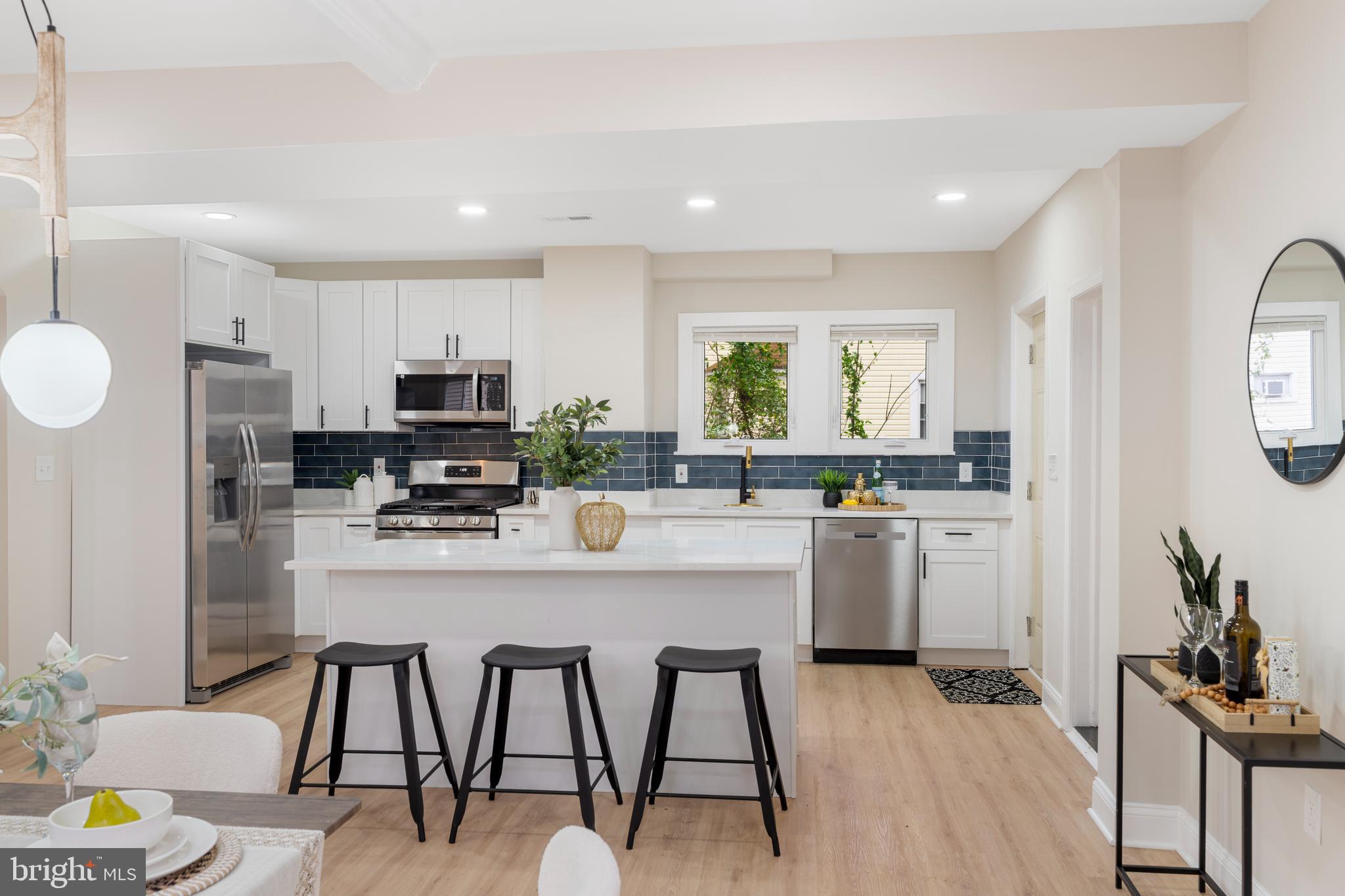 2905 Whitney Avenue Baltimore, MD 21215 - Photo 13 of 36 a kitchen with stainless steel appliances kitchen island granite countertop a refrigerator a stove a sink dishwasher and white cabinets with wooden floor