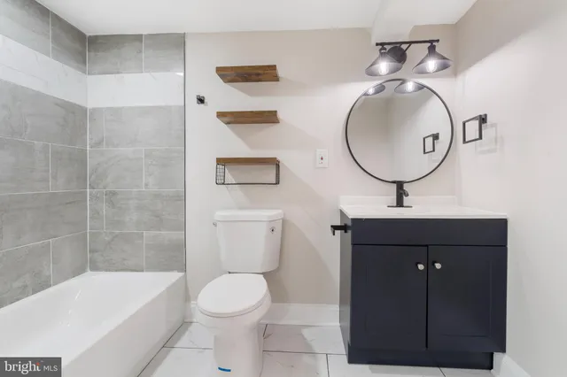 a bathroom with a toilet sink vanity tub and mirror