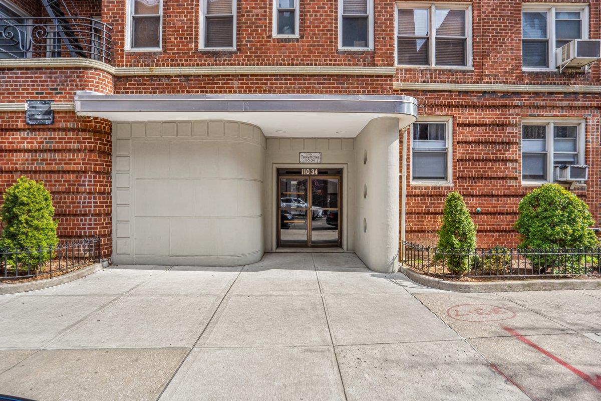 110-34 73rd Road, Unit 6J Queens, NY 11375 - Photo 1 of 1 View of exterior entry featuring brick siding, concrete driveway, and a garage
