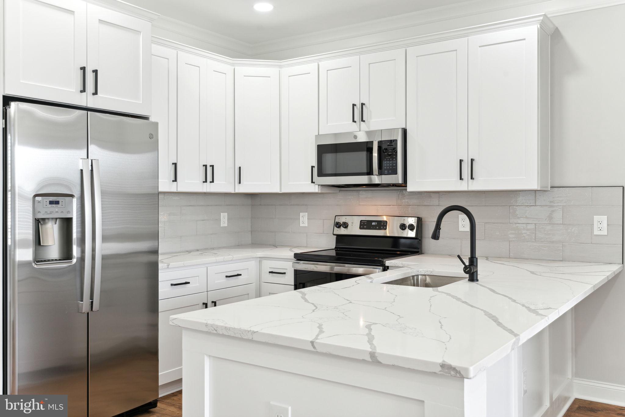 a kitchen with stainless steel appliances granite countertop a refrigerator a stove a sink and white cabinets