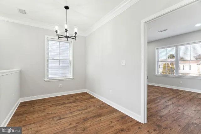 an empty room with wooden floor exposed radiator and windows