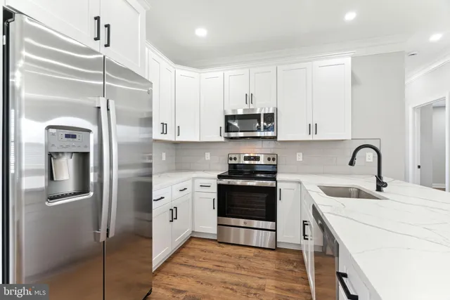 a kitchen with stainless steel appliances a refrigerator sink and white cabinets
