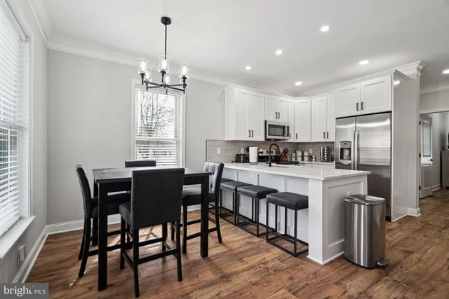 a kitchen with stainless steel appliances granite countertop a dining table chairs stove refrigerator and cabinets