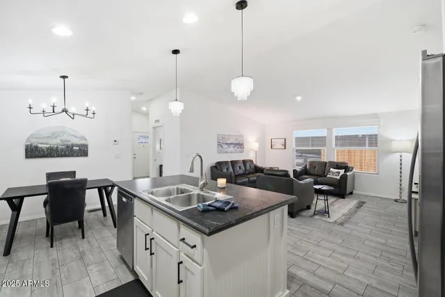 a kitchen with stainless steel appliances kitchen island granite countertop dining table chairs and a refrigerator