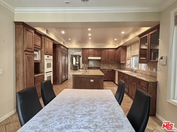 a large kitchen with stainless steel appliances kitchen island granite countertop a refrigerator a sink a stove a microwave and island