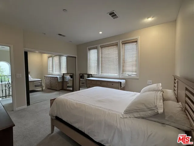 a bedroom with a large bed and windows