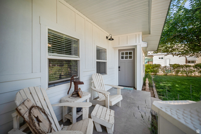 236 West 300 South Hurricane, UT 84737 - Photo 7 of 76 Covered porch featuring white vertical siding, a gray entry door with windowpanes, and an exterior sconce