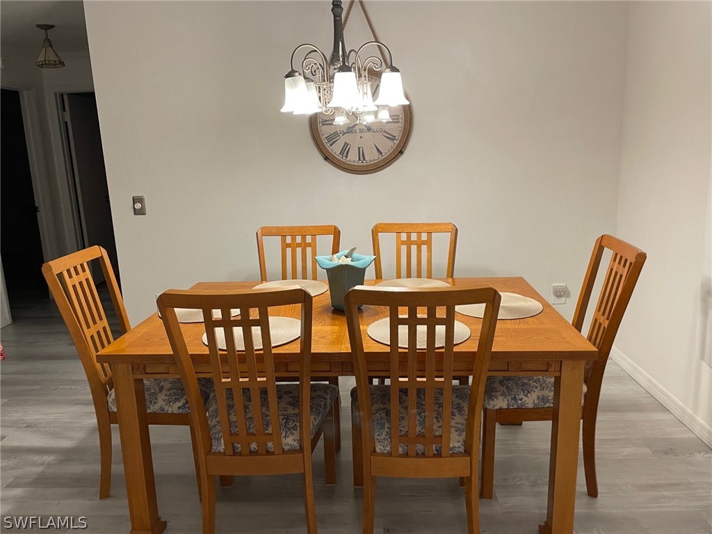 11731 Iona Road Fort Myers, FL 33908 - Photo 6 of 26 a view of a dining room with furniture wooden floor and a chandelier