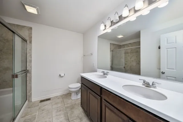 a bathroom with a double vanity sink mirror and toilet