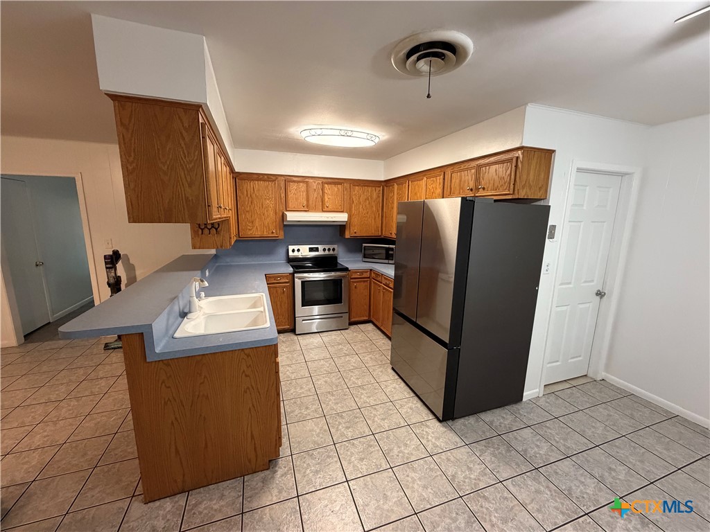 3504 Erwin Avenue Victoria, TX 77901 - Photo 3 of 16 a kitchen with stainless steel appliances a refrigerator a sink a stove top oven and a counter top space