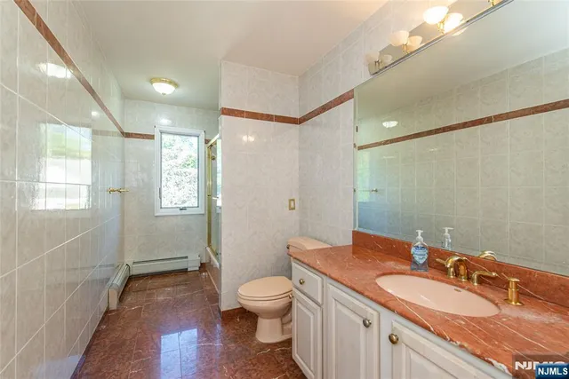 a bathroom with a granite countertop double vanity sink a mirror and a toilet
