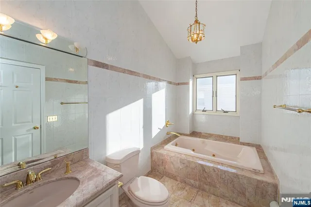 a bathroom with a granite countertop tub a sink and a large mirror