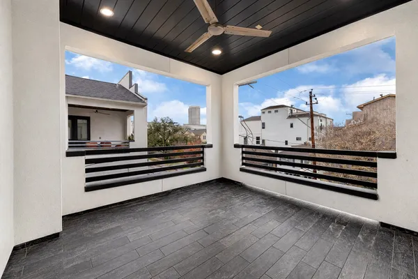 an empty room with wooden floor fan and windows