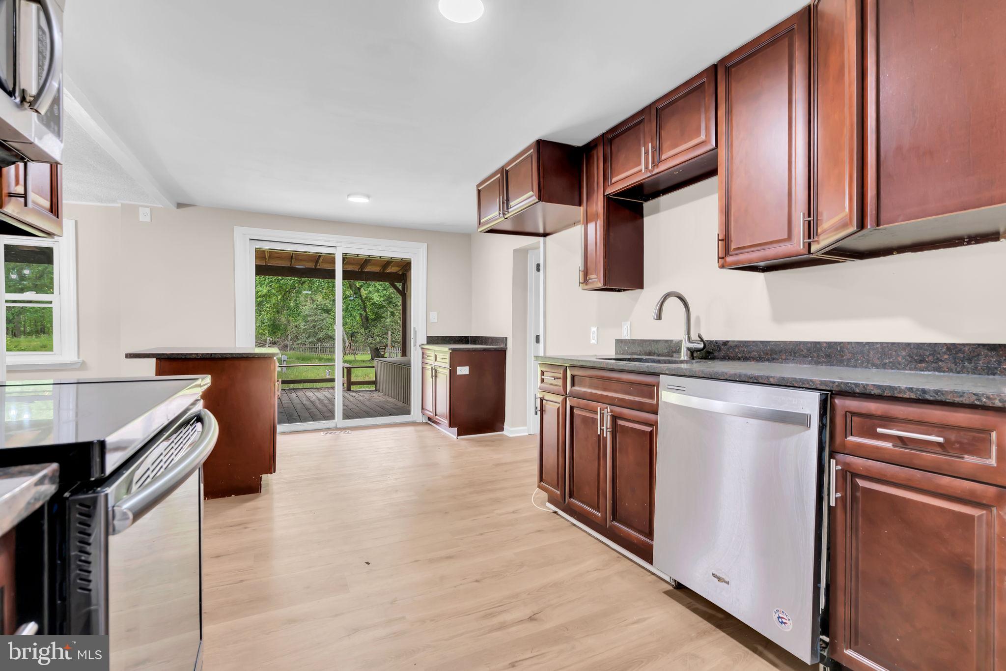 2438 Range Road Browns Mills, NJ 08015 - Photo 15 of 61 a kitchen with stainless steel appliances granite countertop a stove top oven a sink dishwasher a dining table and chairs with wooden floor