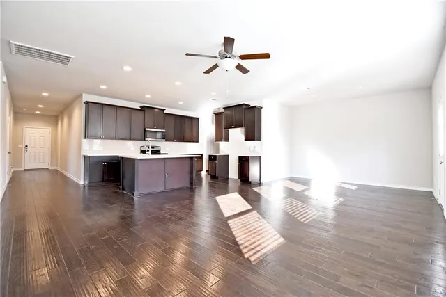 a living room with stainless steel appliances kitchen island hardwood floor and a view of kitchen