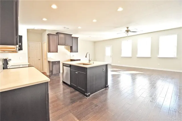 a large kitchen with kitchen island a sink a stove a refrigerator and a dining table with wooden floor