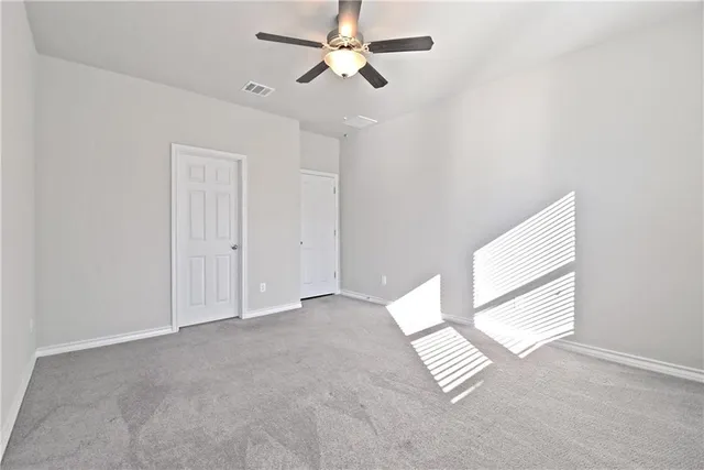 an empty room with windows and fan