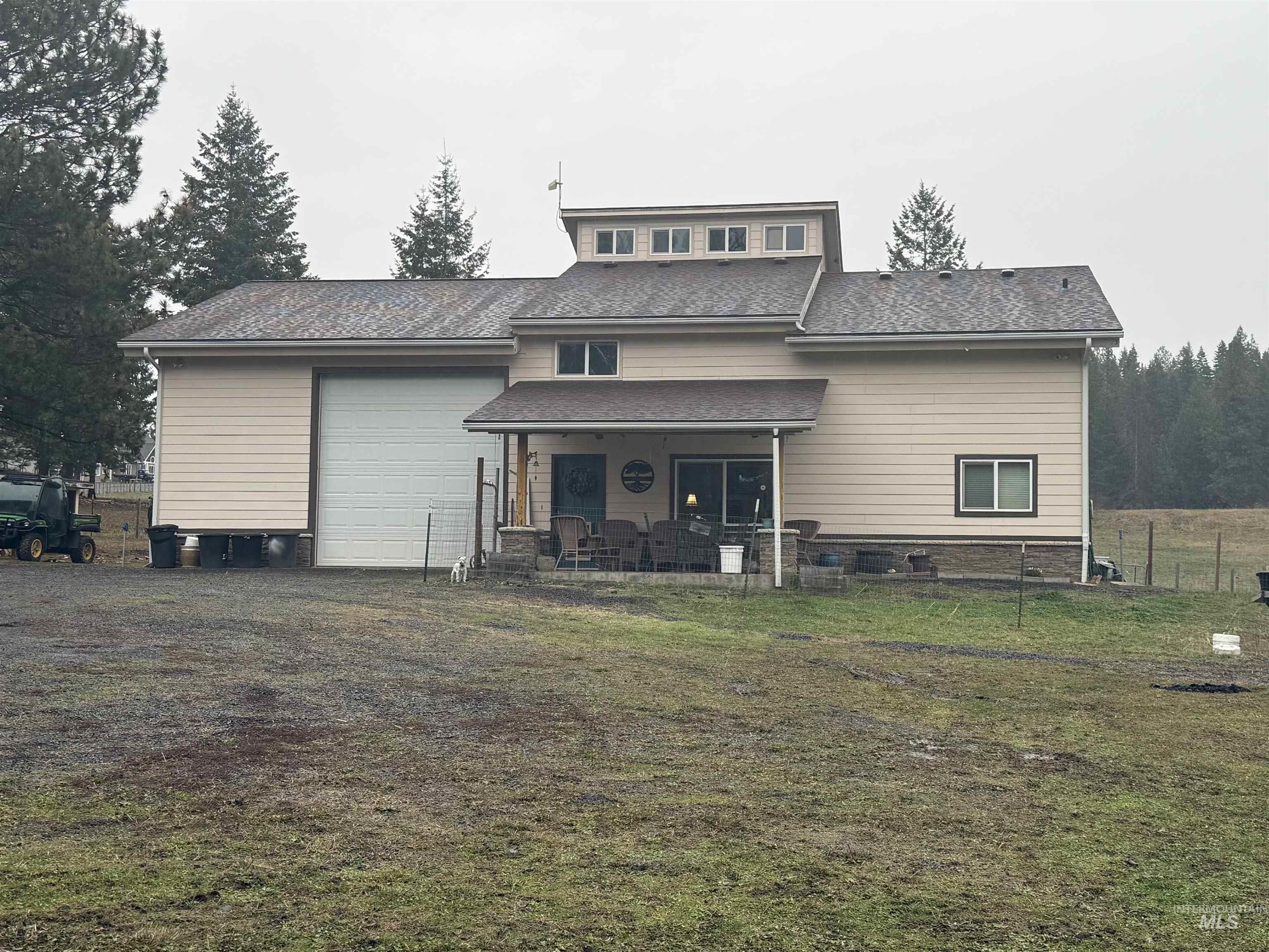 Back of house featuring a shingled roof, a patio, and a garage