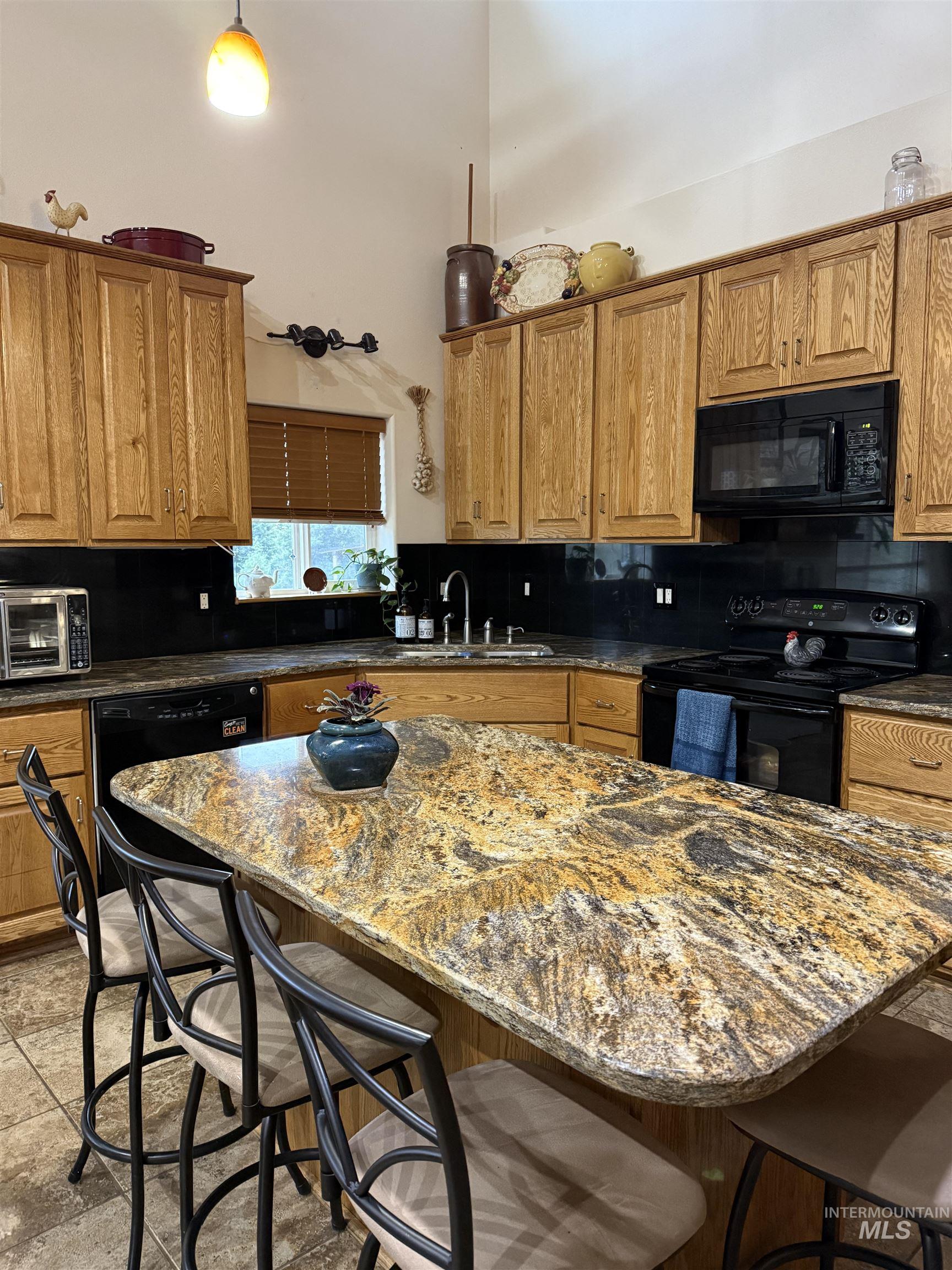 1653 Kidder Ridge Road Kamiah, ID 83536 - Photo 5 of 47 Kitchen with a kitchen breakfast bar, brown cabinets, black appliances, dark stone counters, and a center island
