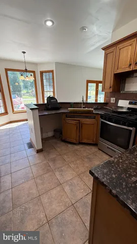 a kitchen with stainless steel appliances kitchen island granite countertop a refrigerator and a stove top oven