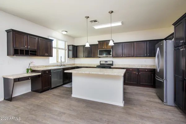a kitchen with kitchen island a counter top space a refrigerator cabinets and a sink